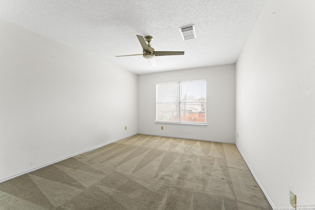 empty room with ceiling fan, light colored carpet, and a textured ceiling