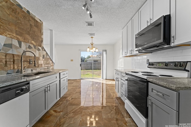 kitchen featuring electric stove, sink, gray cabinets, dishwasher, and dark stone countertops