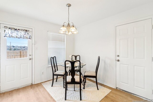 dining space with light wood-type flooring, an inviting chandelier, and baseboards