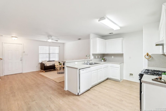 kitchen with gas range oven, light countertops, white cabinets, white dishwasher, and a peninsula
