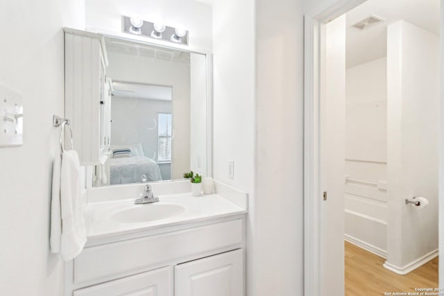 full bath with ensuite bath, visible vents, wood finished floors, and vanity