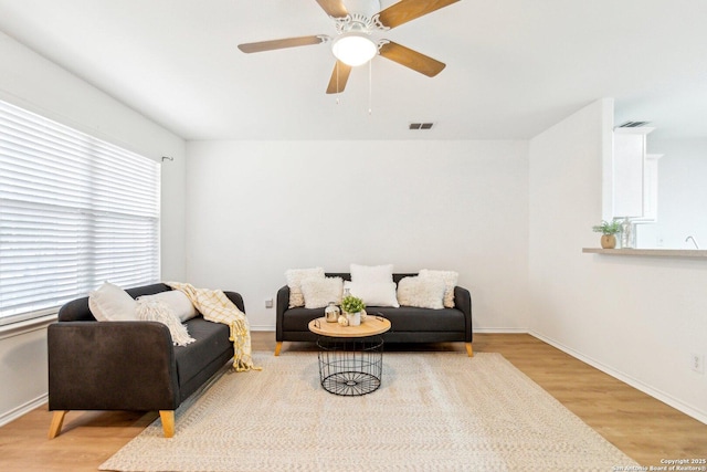 living room featuring baseboards, visible vents, and wood finished floors