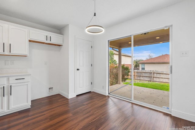 unfurnished dining area with dark wood-type flooring