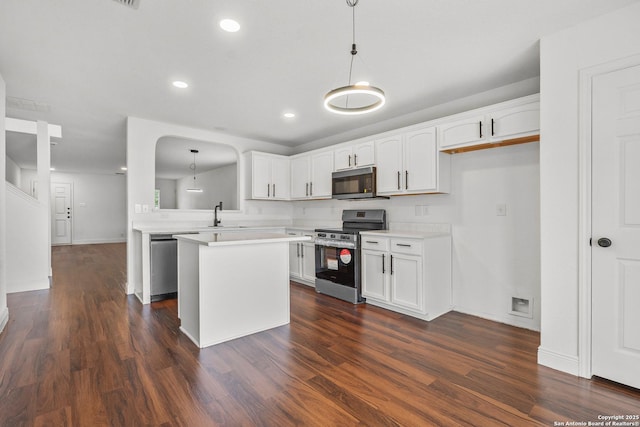 kitchen featuring white cabinetry, stainless steel appliances, kitchen peninsula, and hanging light fixtures