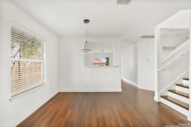 unfurnished dining area featuring dark hardwood / wood-style floors and a textured ceiling