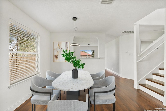 dining room featuring dark hardwood / wood-style flooring and a textured ceiling