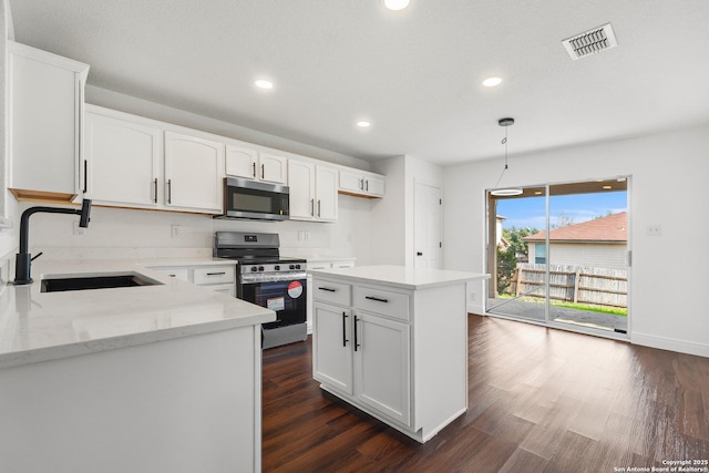 kitchen with white cabinetry, sink, a center island, stainless steel appliances, and light stone countertops