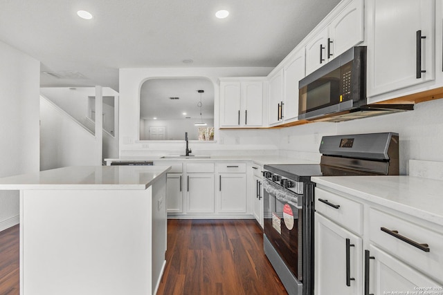 kitchen with dark wood-type flooring, sink, white cabinetry, appliances with stainless steel finishes, and a kitchen island