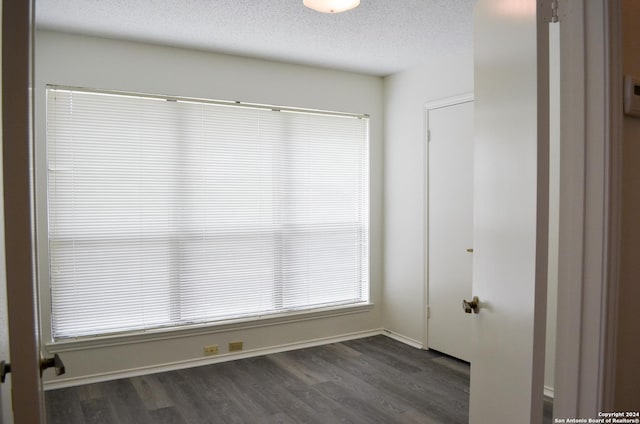 unfurnished room with dark hardwood / wood-style flooring and a textured ceiling