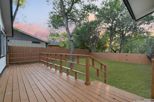 deck at dusk featuring a lawn