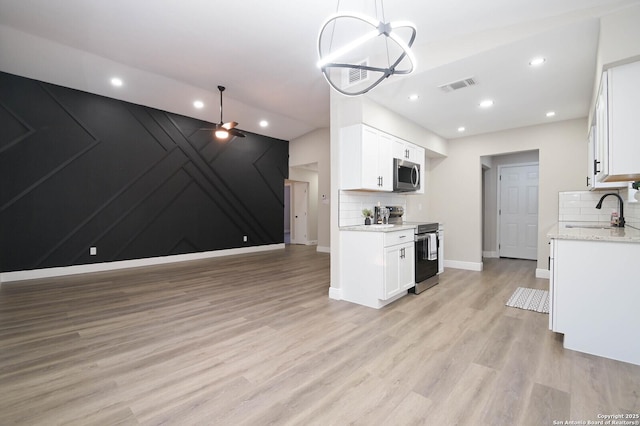 kitchen featuring white cabinetry, sink, decorative light fixtures, and appliances with stainless steel finishes