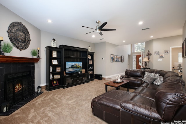 carpeted living room with ceiling fan and a tile fireplace