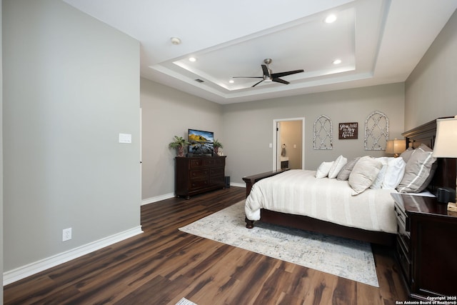 bedroom featuring dark wood-type flooring, a raised ceiling, and ceiling fan