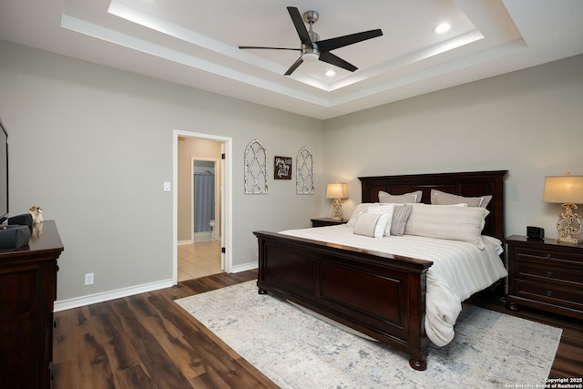 bedroom with a raised ceiling, dark hardwood / wood-style floors, and ceiling fan