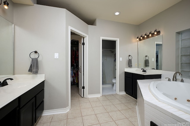 bathroom with tile patterned floors, toilet, tiled bath, and vanity