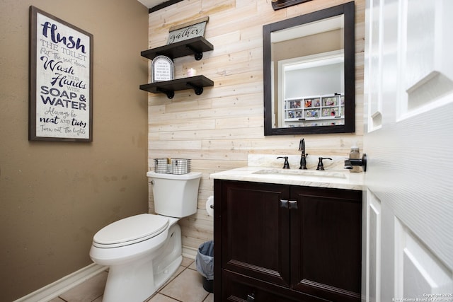 bathroom featuring tile patterned flooring, vanity, wooden walls, and toilet