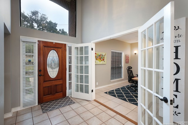 foyer with a towering ceiling, french doors, and light tile patterned flooring