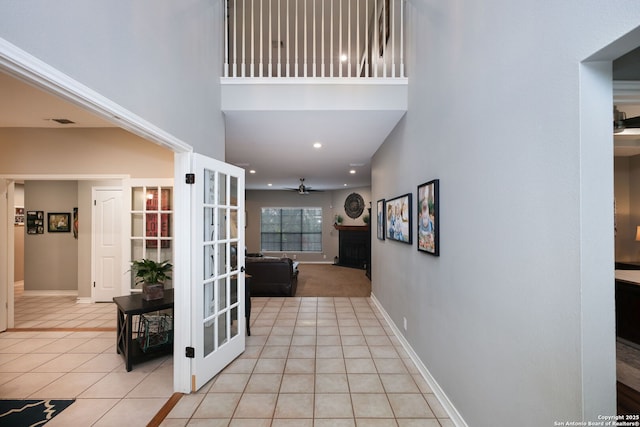 hall with light tile patterned floors, a towering ceiling, and french doors