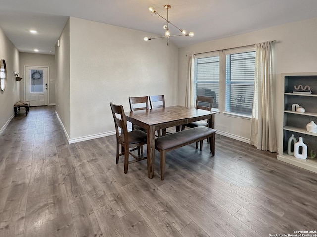 dining space with an inviting chandelier, hardwood / wood-style flooring, and vaulted ceiling