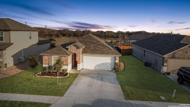 single story home featuring a garage, a yard, and central AC unit