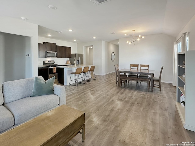 living room featuring lofted ceiling, an inviting chandelier, and light wood-type flooring