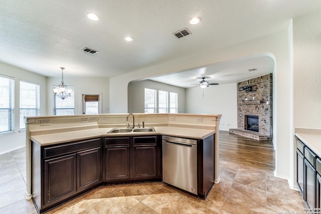 kitchen featuring sink, dark brown cabinets, dishwasher, an island with sink, and pendant lighting