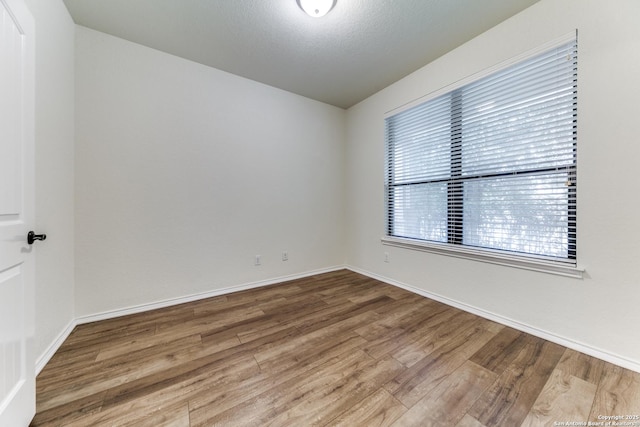 unfurnished room with hardwood / wood-style floors and a textured ceiling