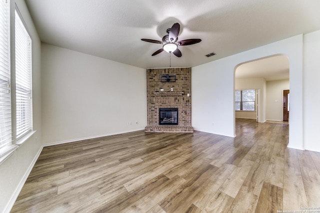 unfurnished living room featuring ceiling fan, a textured ceiling, a fireplace, and wood-type flooring