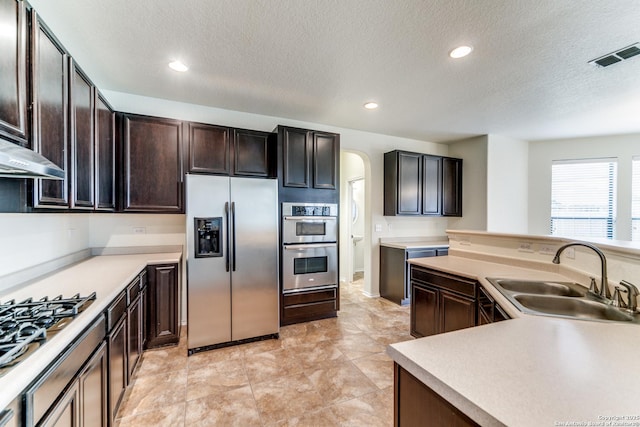 kitchen featuring appliances with stainless steel finishes, sink, a textured ceiling, and dark brown cabinets