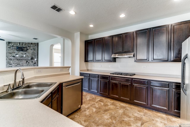 kitchen featuring appliances with stainless steel finishes, sink, a textured ceiling, and dark brown cabinets