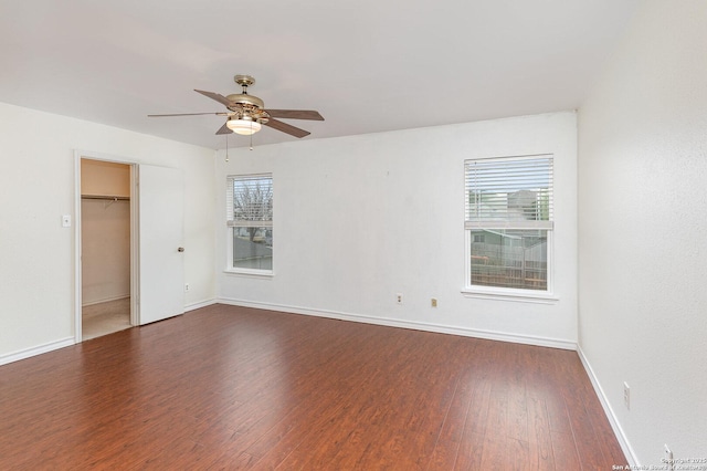 empty room with ceiling fan, dark hardwood / wood-style flooring, and a wealth of natural light