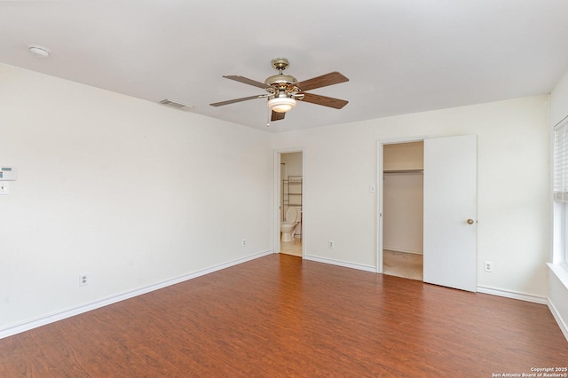 unfurnished bedroom with dark wood-type flooring, ensuite bath, a spacious closet, a closet, and ceiling fan