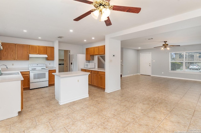 kitchen with ceiling fan, a kitchen island, sink, and white appliances