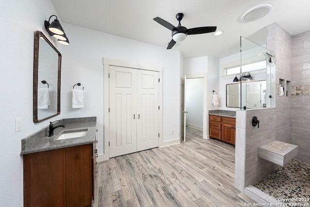 bathroom with ceiling fan, vanity, hardwood / wood-style floors, and a tile shower