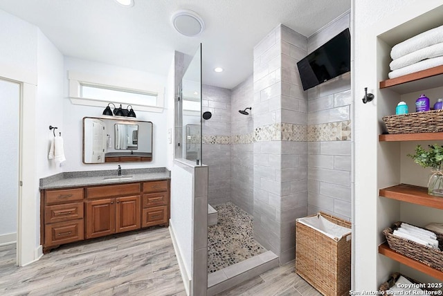 bathroom with vanity, wood-type flooring, and a tile shower