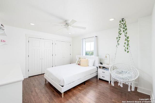 bedroom featuring multiple closets, ceiling fan, and dark hardwood / wood-style flooring