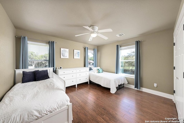 bedroom with multiple windows, dark wood-type flooring, and ceiling fan