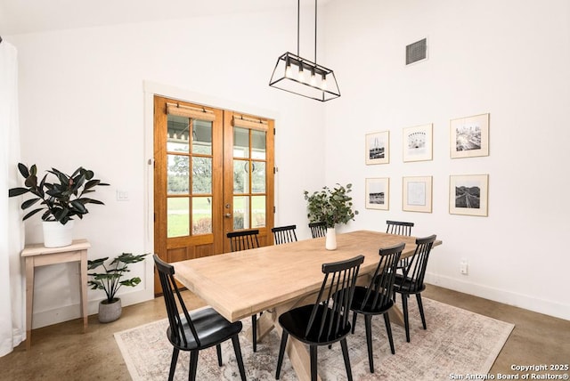 dining area featuring concrete flooring, french doors, and a high ceiling