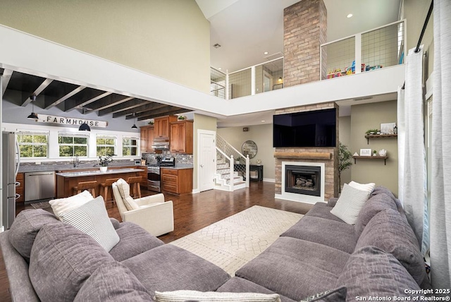 living room with dark hardwood / wood-style floors, sink, a fireplace, and a towering ceiling