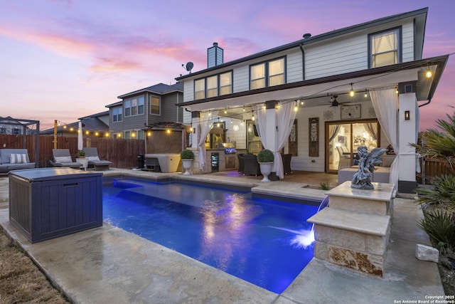 pool at dusk with ceiling fan and a patio