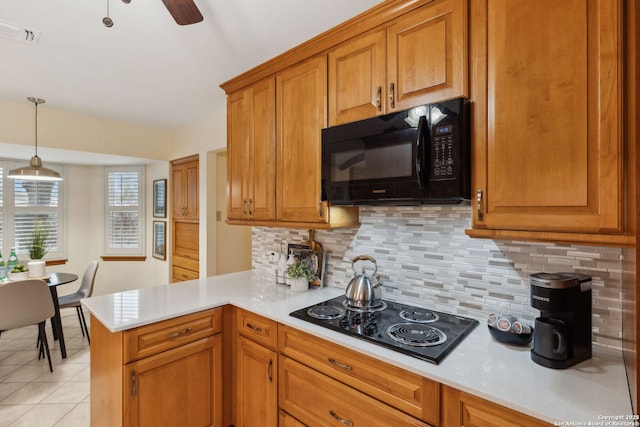 kitchen featuring light tile patterned flooring, decorative light fixtures, black appliances, kitchen peninsula, and backsplash