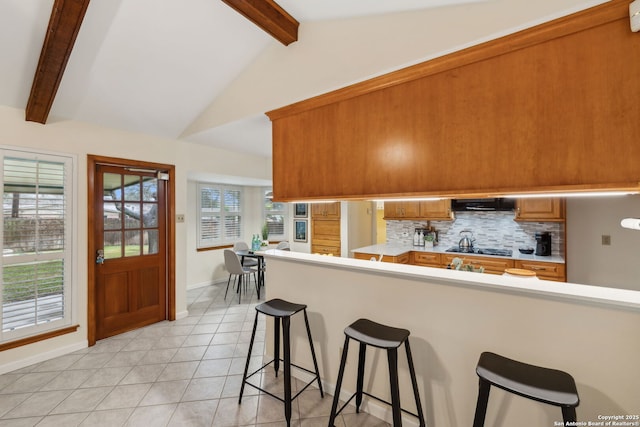 kitchen featuring extractor fan, light tile patterned flooring, a kitchen bar, decorative backsplash, and kitchen peninsula