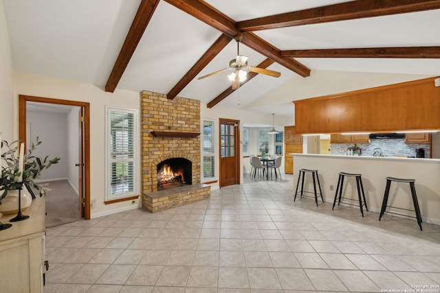 living room featuring light tile patterned floors, a fireplace, vaulted ceiling with beams, and ceiling fan