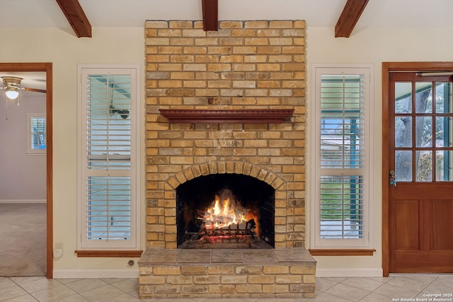 interior details with beamed ceiling, ceiling fan, a fireplace, and carpet