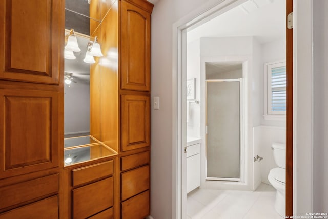 bathroom featuring tile patterned flooring, a shower with door, and toilet