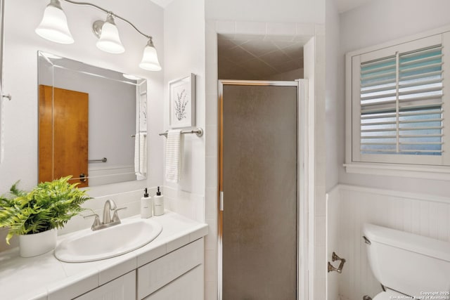 bathroom with toilet, vanity, and a shower with shower door