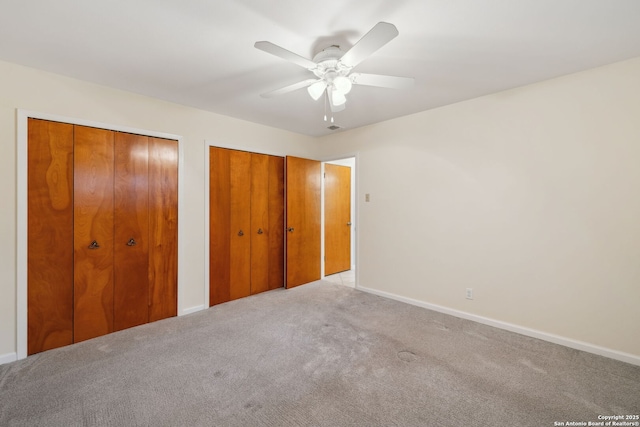 unfurnished bedroom with multiple closets, light carpet, and ceiling fan