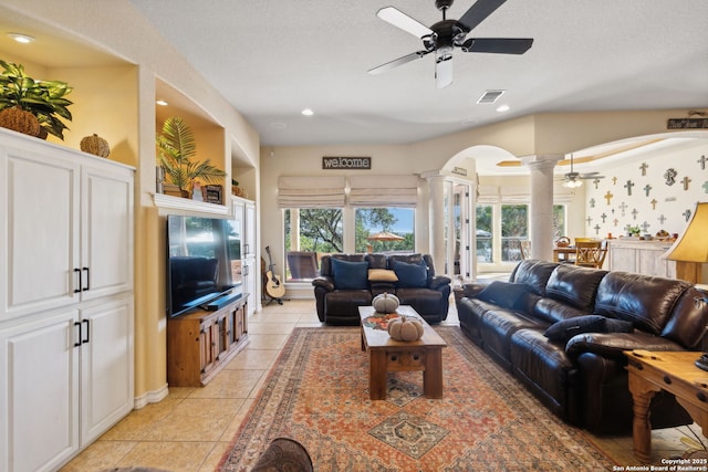 living room featuring light tile patterned flooring, ceiling fan, a wealth of natural light, and ornate columns