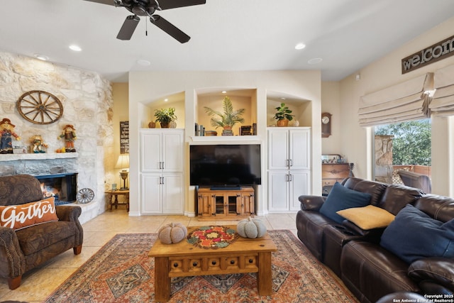 tiled living room with ceiling fan and a fireplace