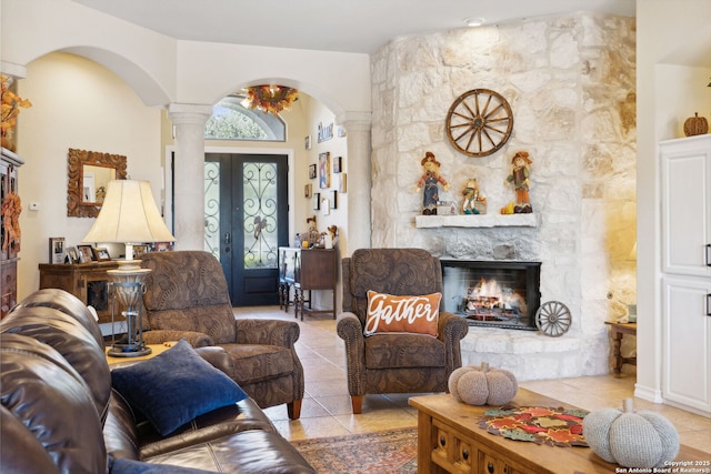 tiled living room with ornate columns, a fireplace, and french doors